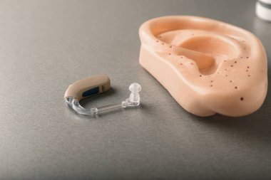 İşitme cihazı ve gri arka plan üzerinde kulak modeli