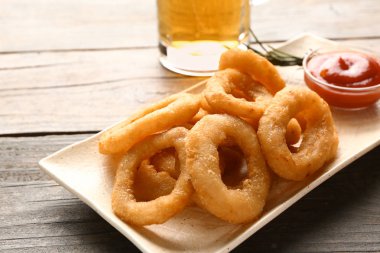 Lezzetli soğan halkaları ve ahşap masa sosu ile plaka