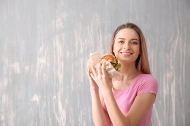 Lezzetli burger gri arka plan üzerinde olan güzel kadın