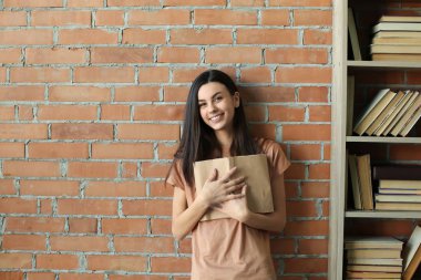 Yakınındaki duvara kitaplığındaki kitap ile güzel genç kadın