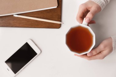 Beyaz masada sıcak çay ile eller