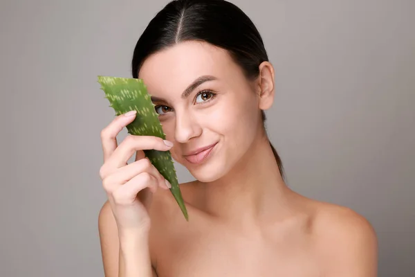 Portrait of beautiful woman with aloe vera on grey background — Stock Photo, Image