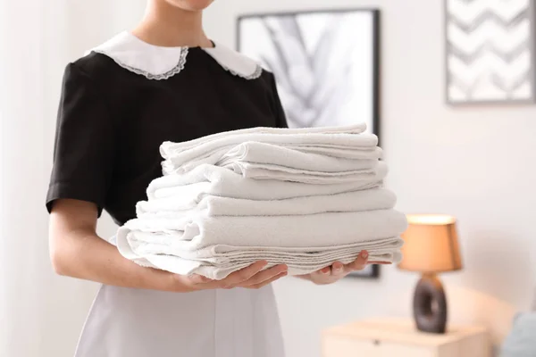 Bela governanta feminina com toalhas limpas no quarto, close-up — Fotografia de Stock