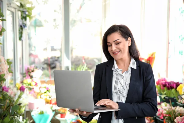 Güzel kadın sahibi çiçekçi dükkanı içinde laptop ile