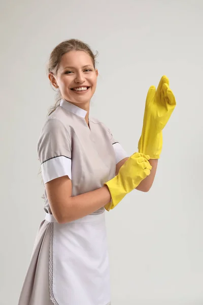 Portret van mooie vrouwelijke huishoudster dragen van handschoenen op witte achtergrond — Stockfoto