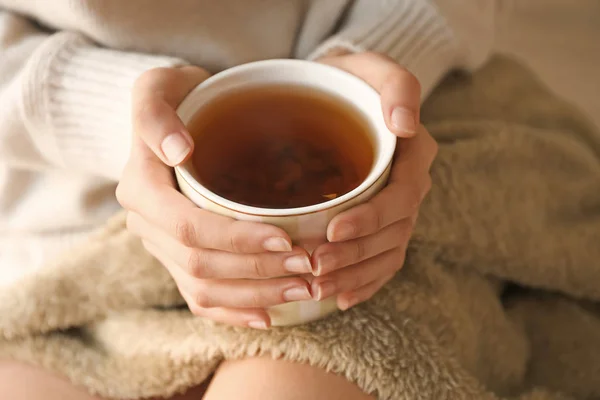 Jeune femme avec une tasse de thé chaud reposant à la maison, gros plan — Photo