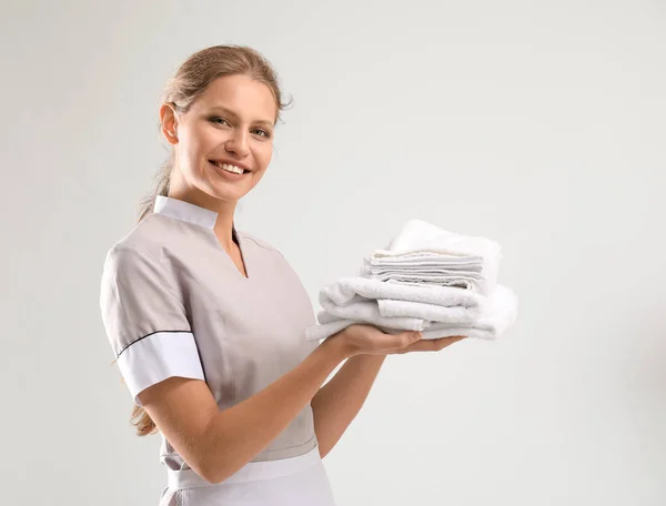 Portrait of beautiful female housekeeper with clean towels on white background — Stock Photo, Image