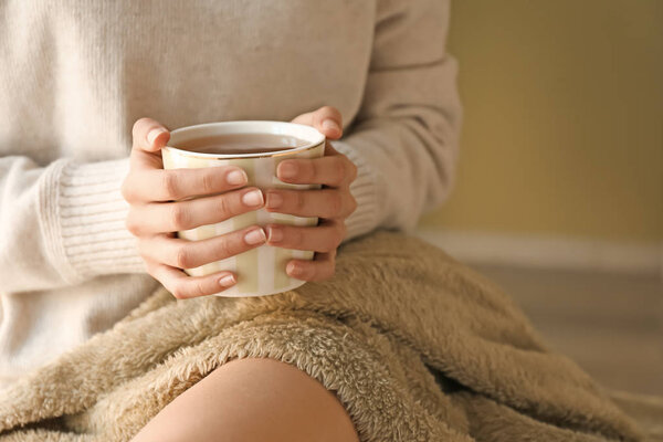Young woman with cup of hot tea resting at home