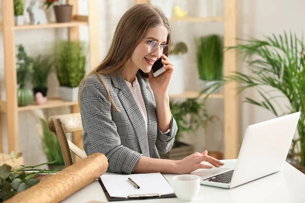 Prachtige vrouwelijke bloemist werken aan tafel in de winkel — Stockfoto