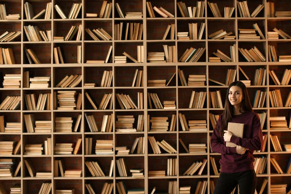A könyvtárban a könyv a gyönyörű fiatal nő portréja — Stock Fotó