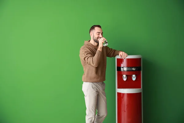 Man drinkwater uit de koeler op kleur achtergrond — Stockfoto