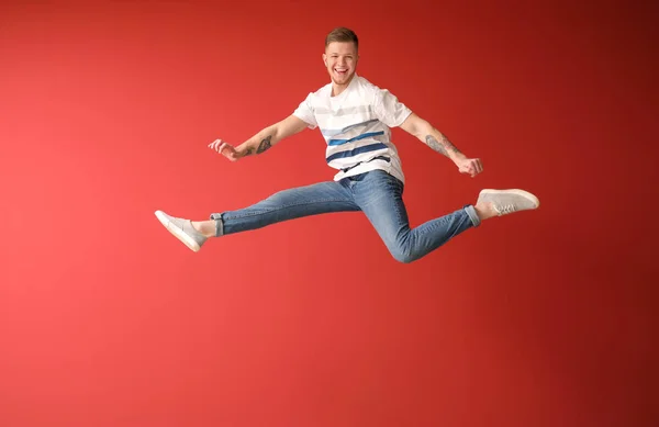 Bonito homem pulando contra fundo de cor — Fotografia de Stock