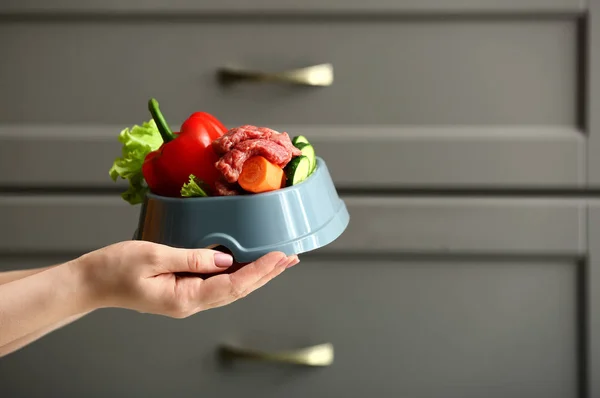 Wanita memegang mangkuk dengan makanan hewan peliharaan segar di dapur — Stok Foto