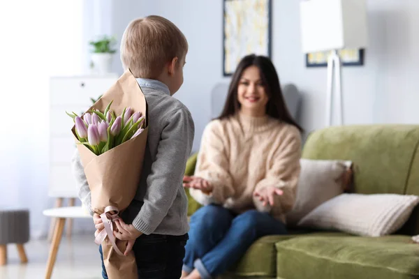 Little boy hiding flowers for his mother behind back. 8 March celebration — Stock Photo, Image