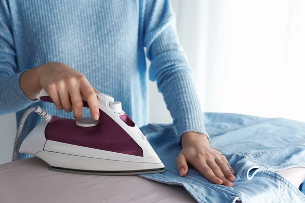 Junge Frau bügelt Kleidung zu Hause — Stockfoto