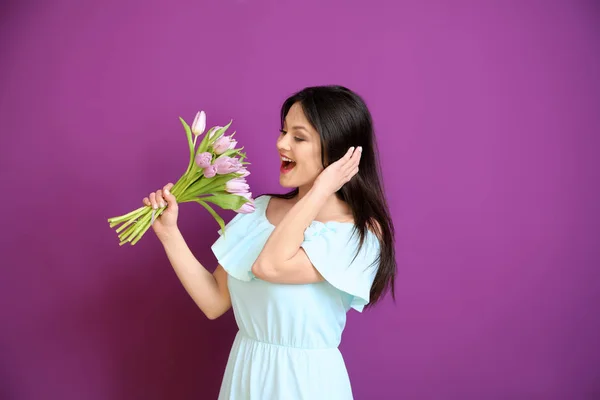 Young woman with bouquet of flowers on color background. 8 March celebration — Stock Photo, Image