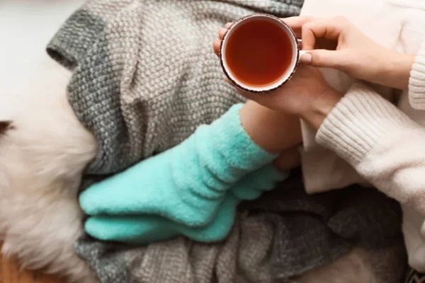 Mujer joven con taza de té caliente sentada en casa — Foto de Stock