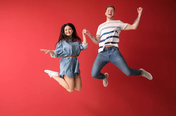 Happy jumping couple against color background — Stock Photo, Image