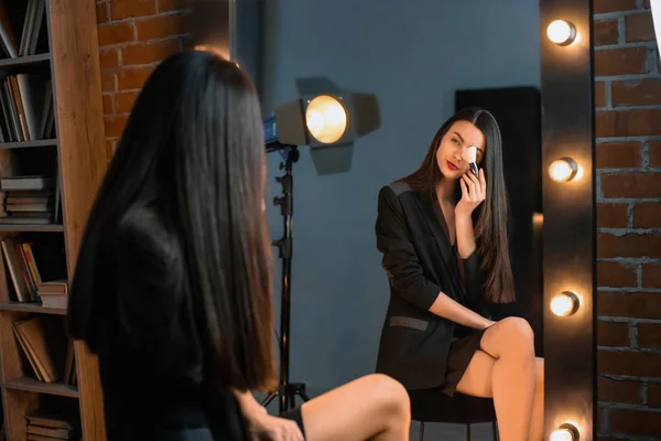 Portrait of beautiful young woman applying makeup near mirror — Stock Photo, Image