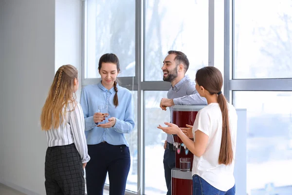 Colegas bebiendo agua del refrigerador durante el descanso en la oficina — Foto de Stock