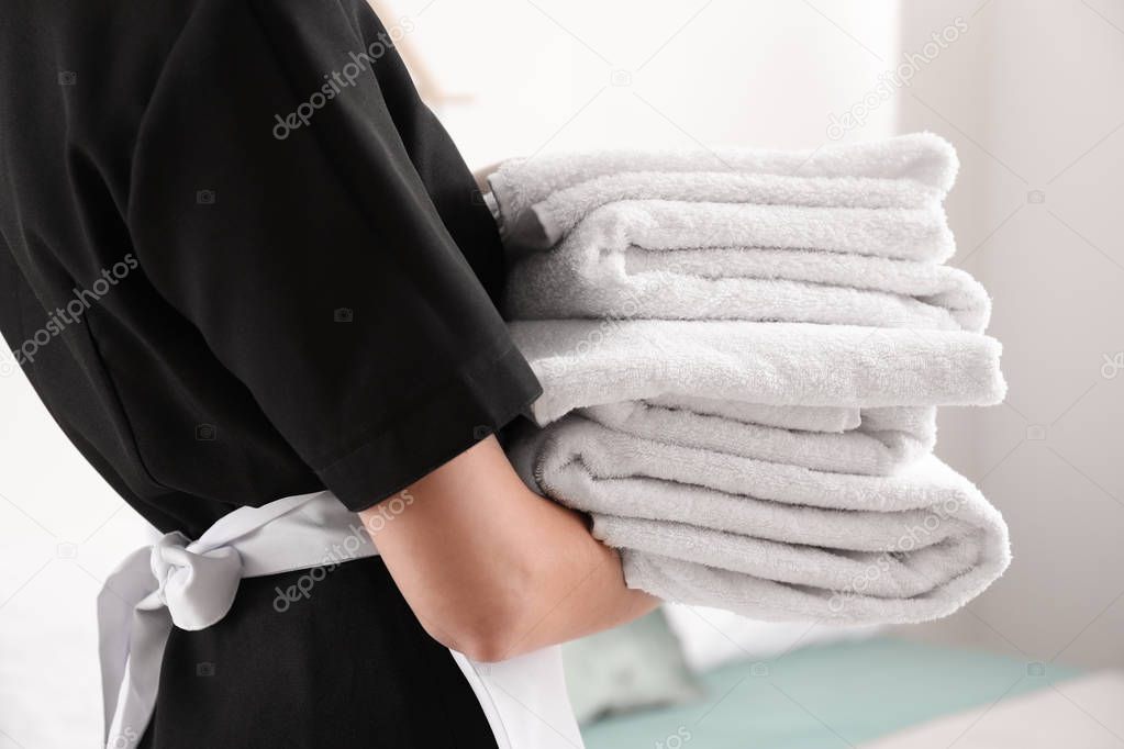 Beautiful female housekeeper with clean towels, closeup
