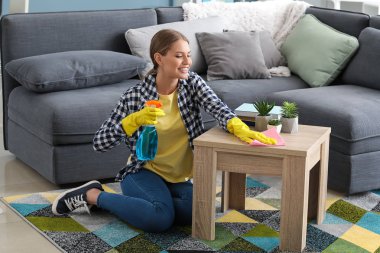 Güzel bir kadın evdeki masayı temizliyor.