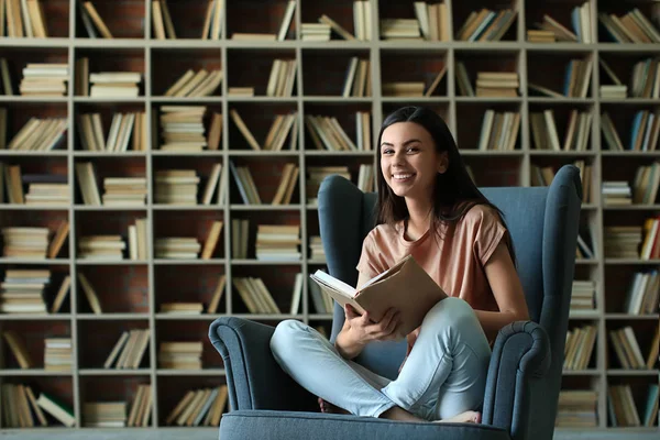 Hermosa joven leyendo libro en la biblioteca — Foto de Stock