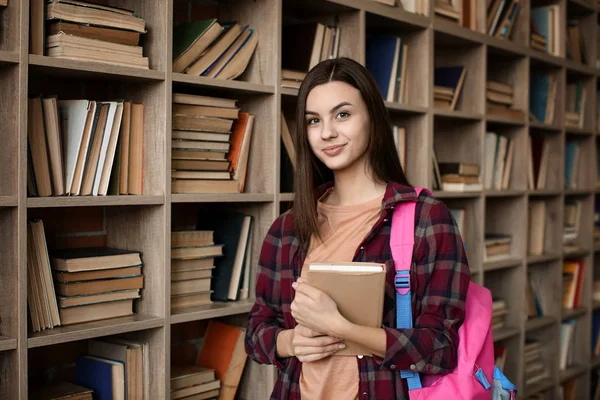 Πορτρέτο του όμορφη νεαρός φοιτητής με το βιβλίο στη βιβλιοθήκη — Φωτογραφία Αρχείου