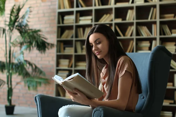Όμορφη νεαρή γυναίκα διαβάζει βιβλίο στη βιβλιοθήκη — Φωτογραφία Αρχείου