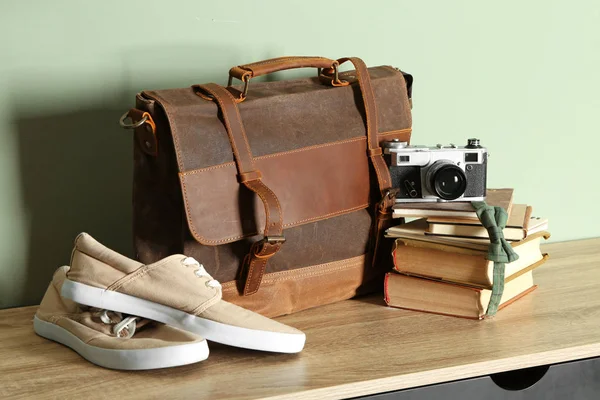 Чоловіче взуття з портфелем, книгами та фотоапаратом на дерев'яному столі — стокове фото