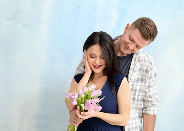 Young man greeting his wife with 8 March on light background — Stock Photo, Image