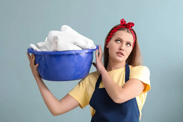 Portrait of beautiful woman with laundry on color background — Stock Photo, Image