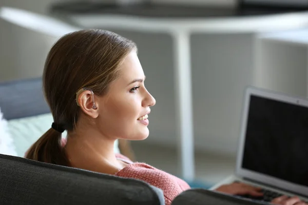 Young woman with hearing aid using laptop at home — Stock Photo, Image