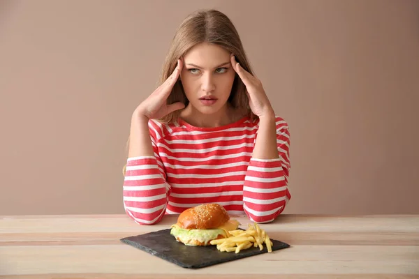 맛 있는 햄버거와 감자 튀김 테이블에 사려깊은 여자 — 스톡 사진