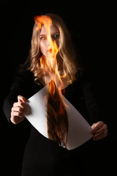 Hermosa joven quemando hoja de papel sobre fondo oscuro —  Fotos de Stock