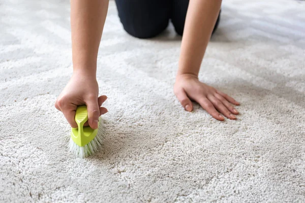 Жінка прибирає килим вдома — стокове фото