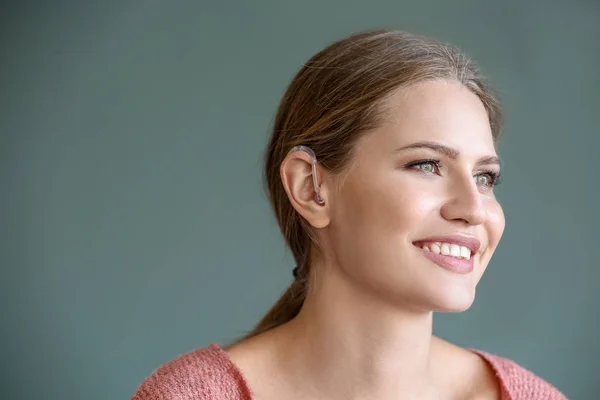 Young woman with hearing on grey background — Stock Photo, Image