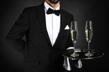 Bardak şampanya koyu arka plan üzerinde ile yakışıklı garson