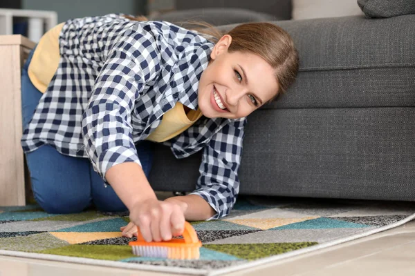 Belle femme nettoyage tapis à la maison — Photo