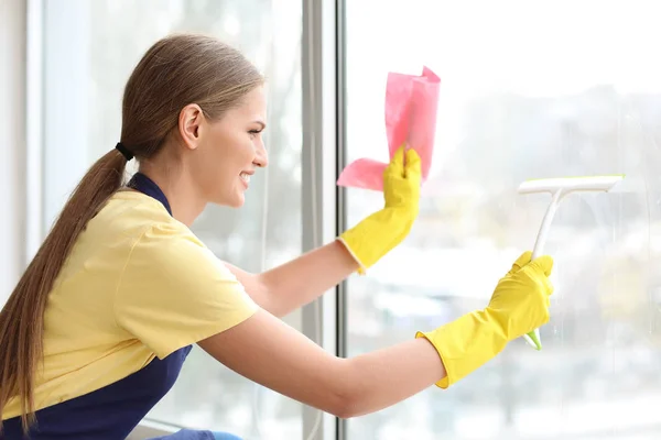 Mooie vrouw schoonmaken raam thuis — Stockfoto