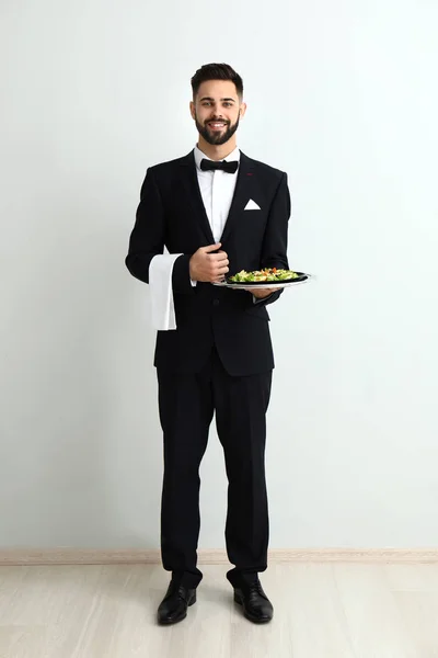 Waiter with fresh salad near light wall — Stock Photo, Image