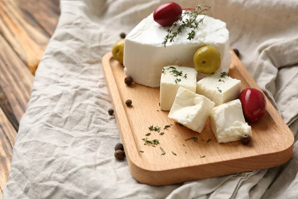 Junta con sabroso queso feta y aceitunas en la mesa —  Fotos de Stock