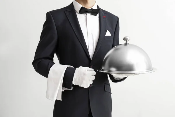 Cameriere con vassoio e cloche su sfondo chiaro — Foto Stock