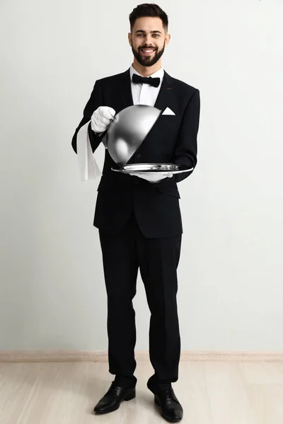 Waiter with tray and cloche near light wall — Stock Photo, Image