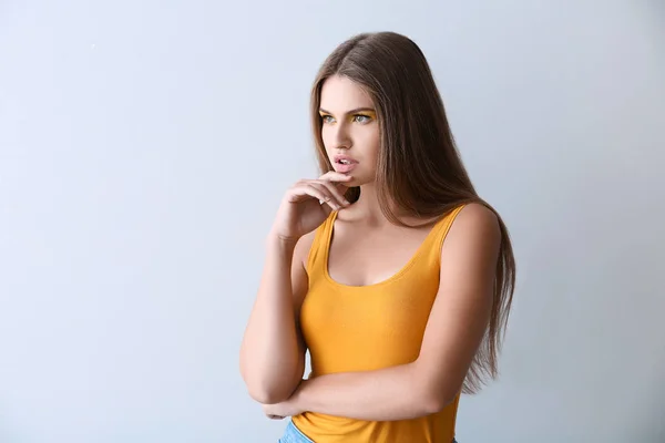 Bella giovane donna con trucco luminoso su sfondo chiaro — Foto Stock