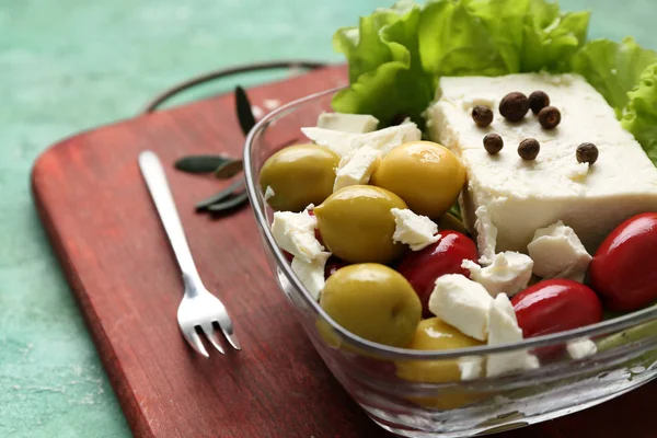 Bowl with tasty feta cheese and olives on wooden board — Stock Photo, Image