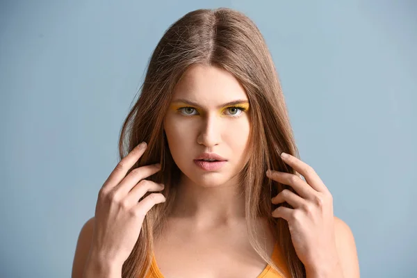 Schöne junge Frau mit hellem Make-up auf farbigem Hintergrund — Stockfoto