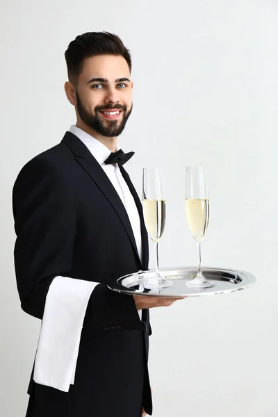 Waiter with glasses of champagne on light background — Stock Photo, Image