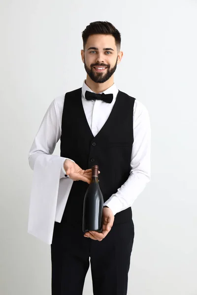 Handsome waiter with bottle of wine on light background — Stock Photo, Image