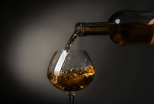 Pouring of wine into glass on dark background — Stock Photo, Image
